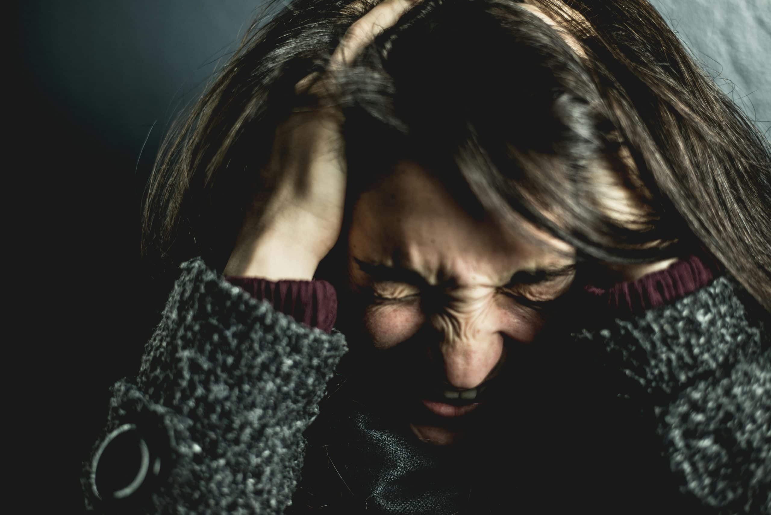 Woman holding her head in frustration with eyes closed tightly, symbolizing financial stress or budget burnout.